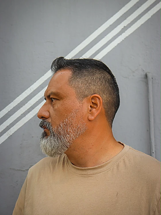 Perfil de un cliente con barba canosa recortada y perfilada.