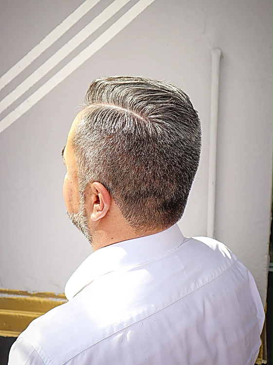 Vista de nuca de un corte con canas, raya lateral y contorno limpio.