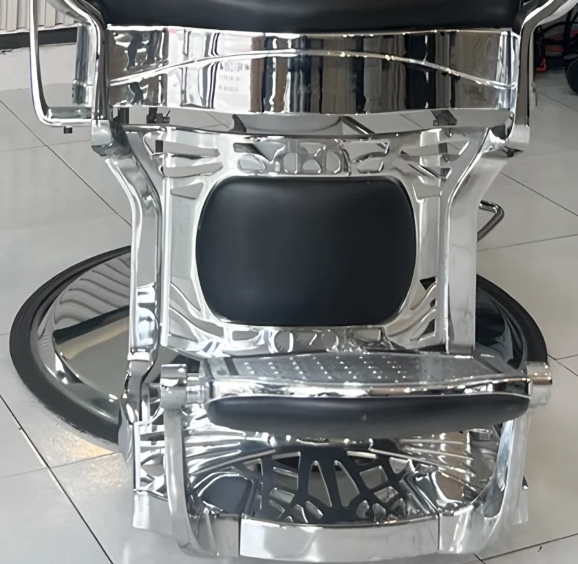 Detalle de la base cromada de la silla de barbero, con el reposapiés labrado.